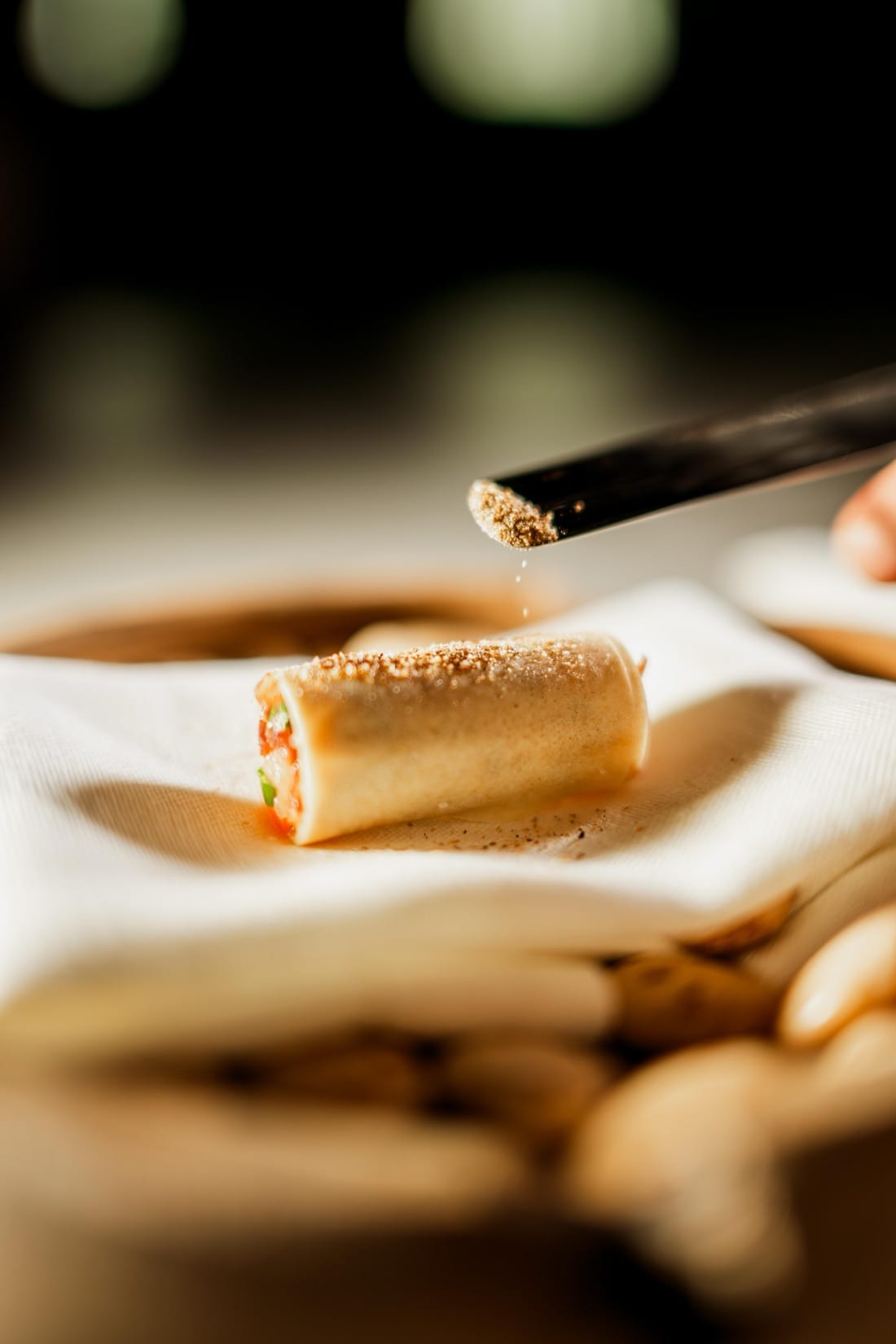 Detalle de emplatado en INIZIO: polvo aromático espolvoreado sobre un canelón
