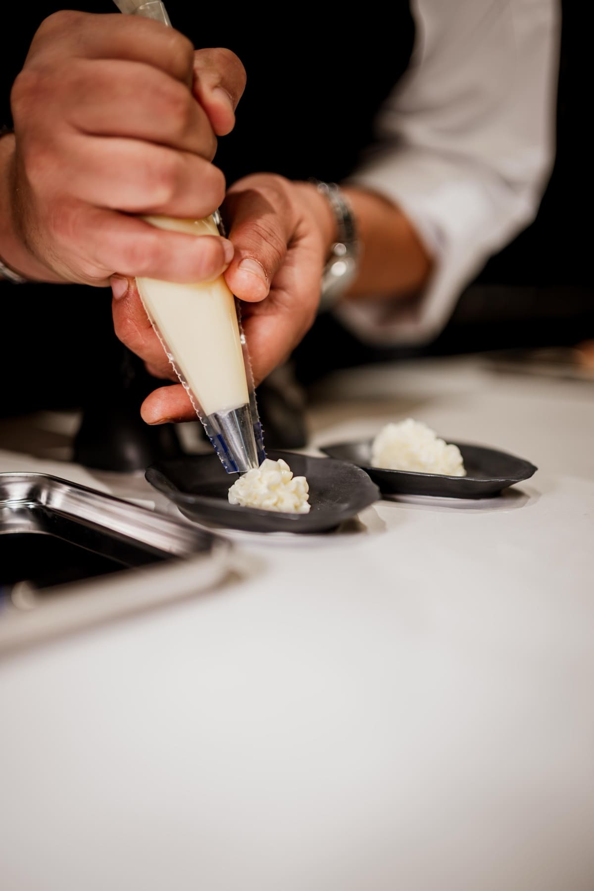 Manos del equipo de cocina emplatando en INIZIO Granada